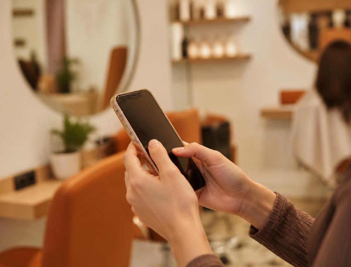 Dłonie trzymające telefon z wiadomością od salonu